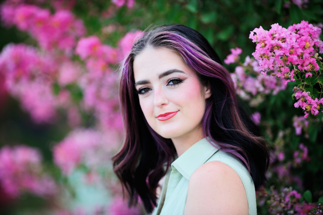 Portrait of a model in front of pink and purple crepe myrtles shot with the Nikon 200mm f/2.0 lens